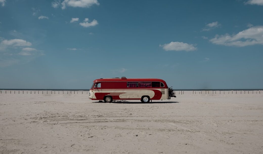 a red and white bus parked on the beach
